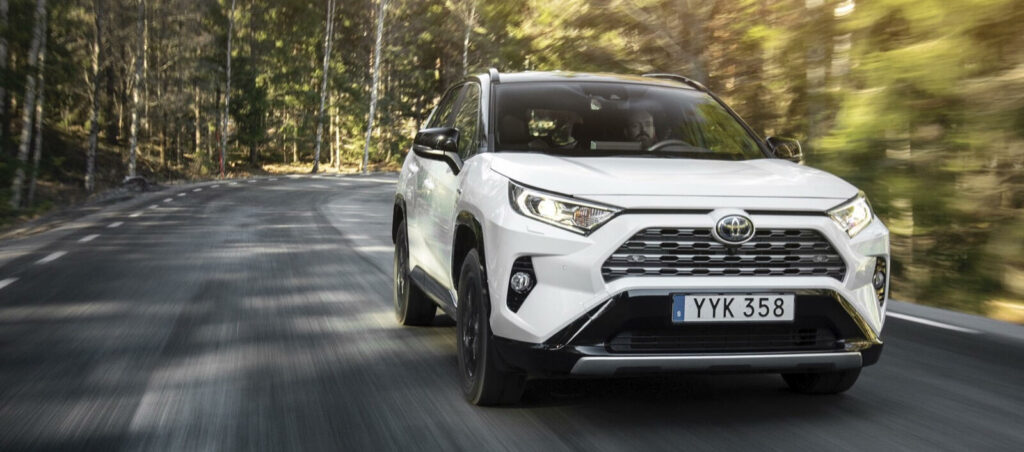 En vit Toyota RAV4 kör genom en landsbygdsväg. (AI text)