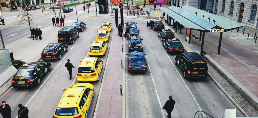 En stadsgata med många bilar och folk (AI text)