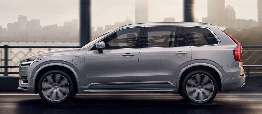 En silverfärgad Volvo XC90 SUV kör på en stadsgata. (AI text)