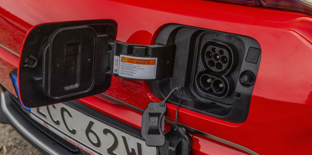 En röd bil står parkerad bredvid en laddstation. (AI text)