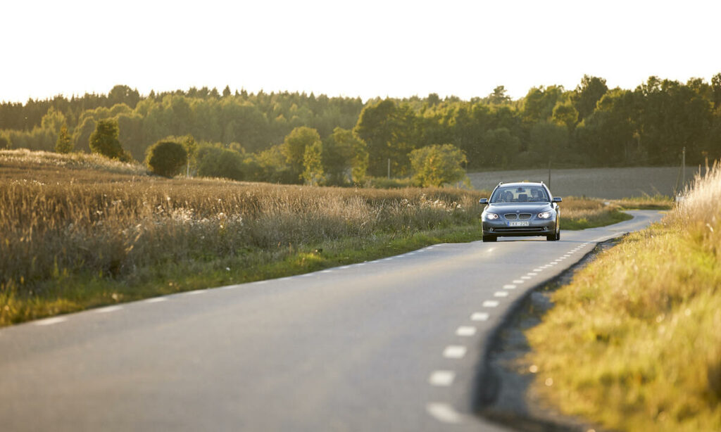 En bil kör nerför en landsväg. (AI text)