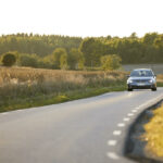 En bil kör nerför en landsväg. (AI text)