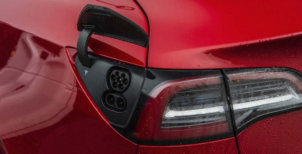 En röd Tesla Model S med rött baklysenheter. (AI text)