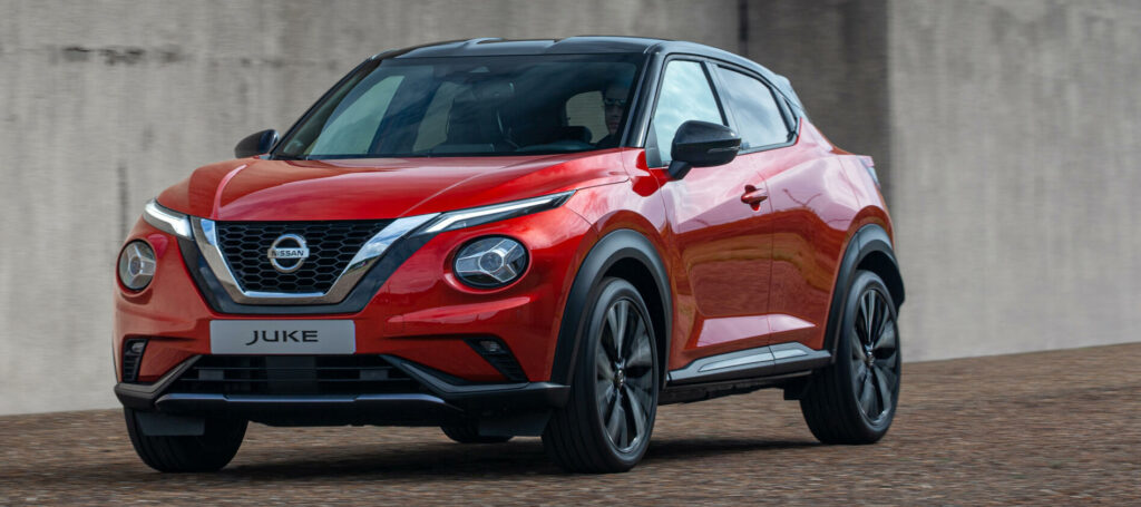 En röd Nissan Juke parkerad framför en betongvägg. (AI text)