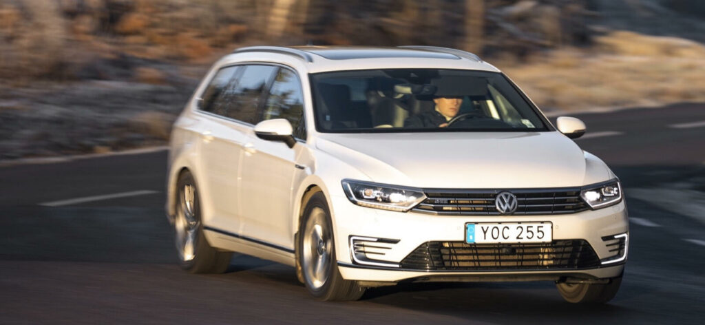 En vit Volkswagen Golf kör nedför en bergsväg. (AI text)