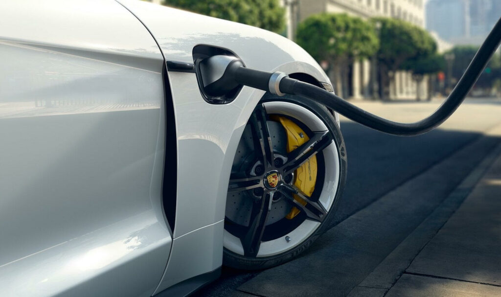 En vit bil är uppkopplad till en elbilsladdare. (AI text)