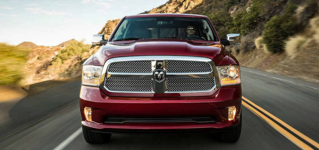 En röd lastbil från märket Ram kör nerför en bergsväg. (AI text)