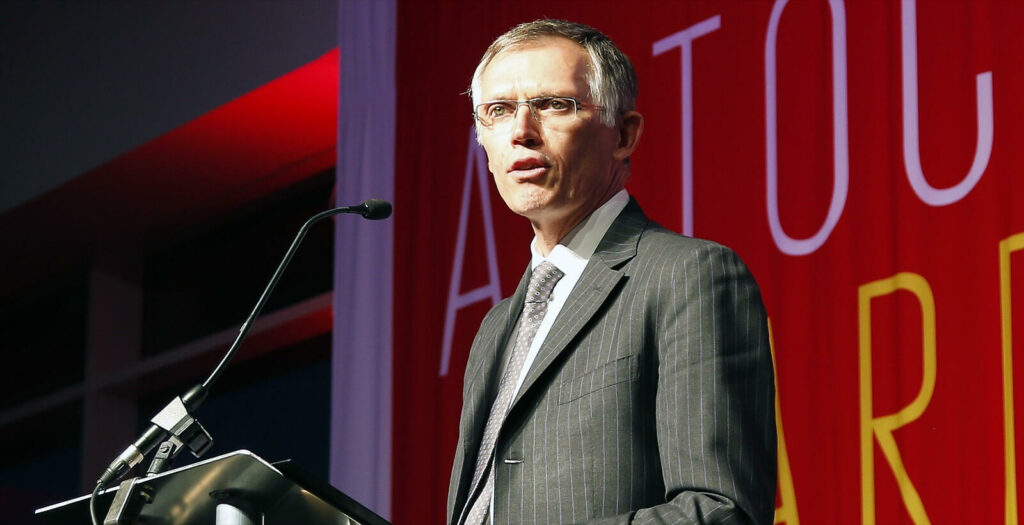 En man i kostym står vid en pult. (AI text)