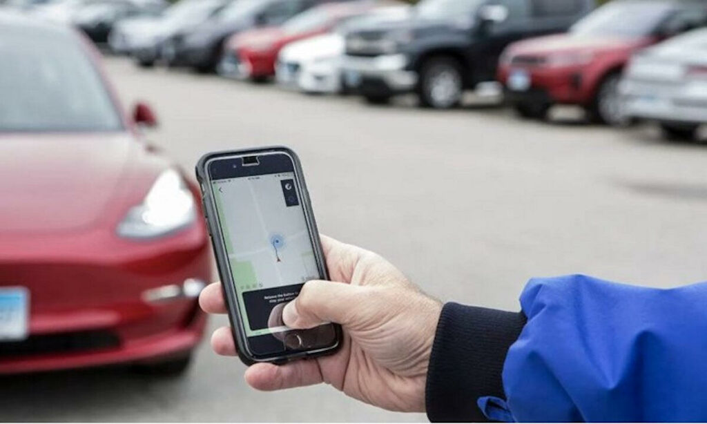 En man använder sin mobil för att kontrollera statusen på hans Tesla elbil. (AI text)