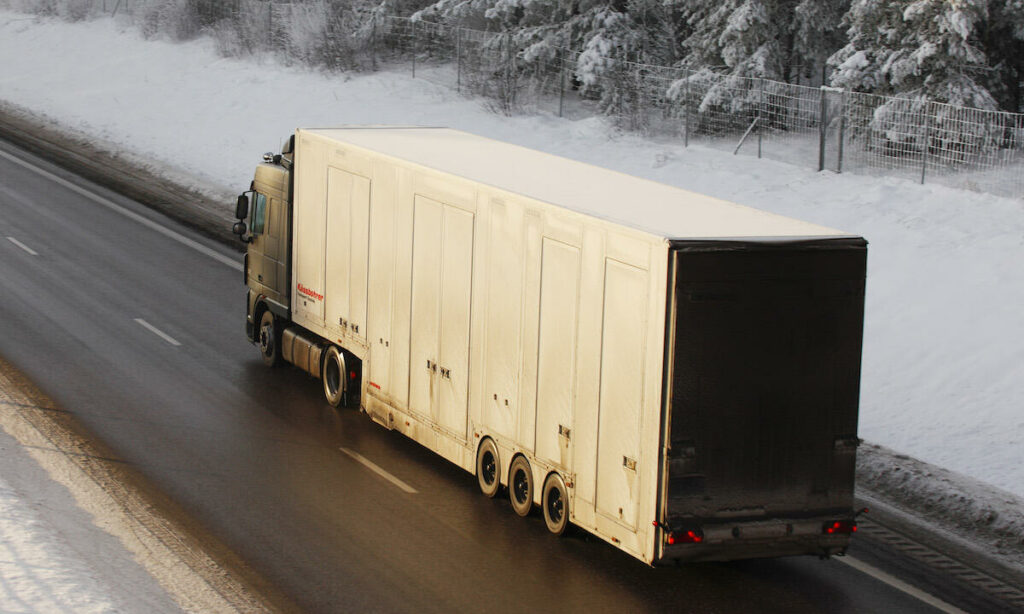 En lastbil kör på en snöig väg. (AI text)