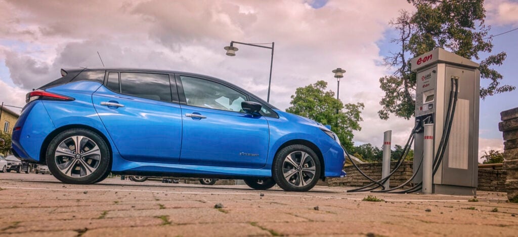En blå Nissan Leaf parkerad vid en laddstation. (AI text)