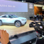 En grupp personer står omkring en bil. (AI text)