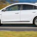 En vit Honda Odyssey kör nerför en landsväg. (AI text)