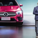 En man står på scenen framför en Mercedes CLA. (AI text)