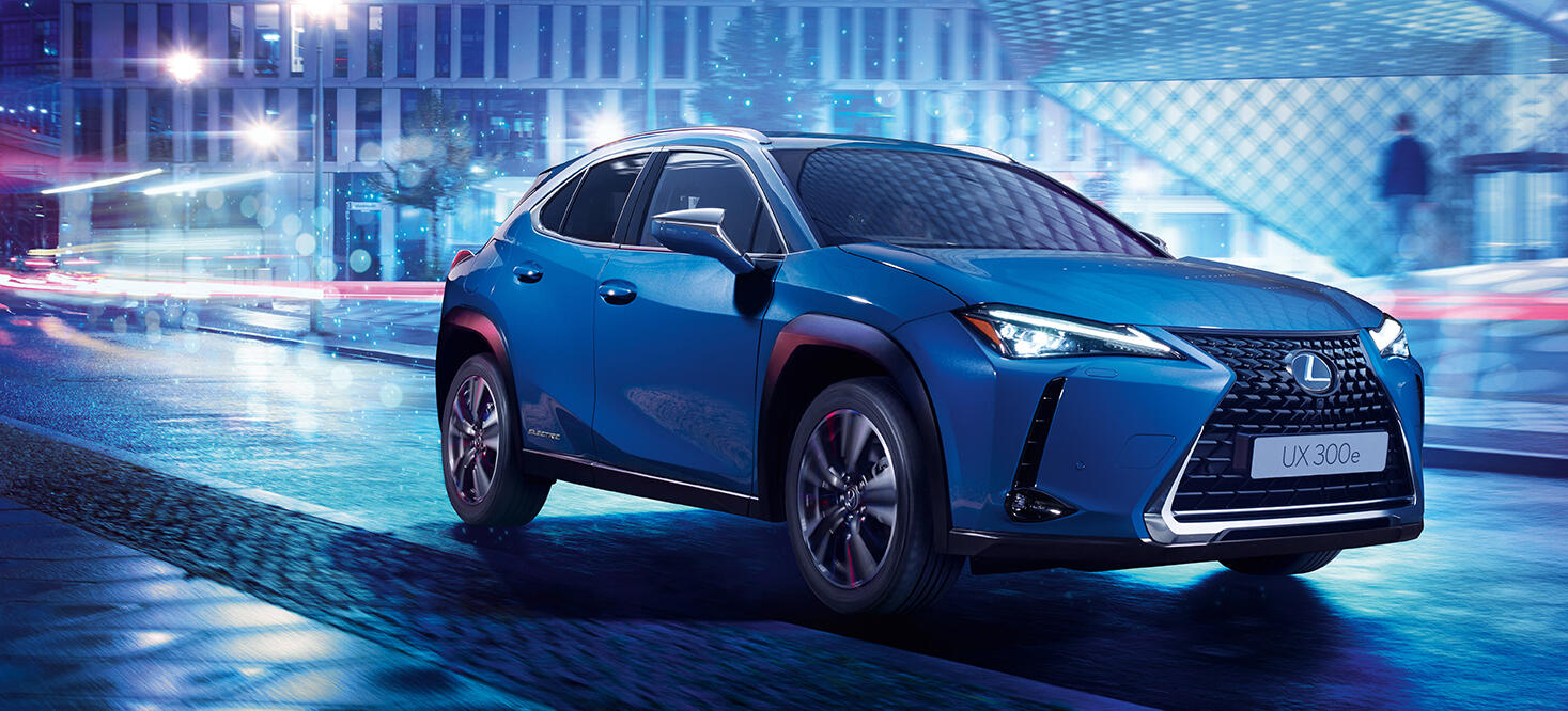 En blå Lexus SUV kör nedför en stadsgata på natten. (AI text)