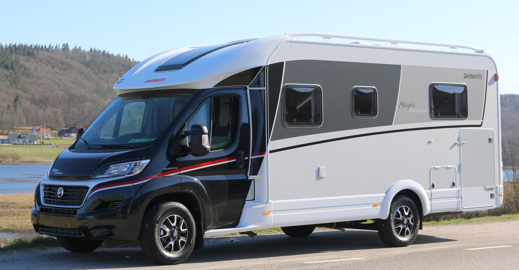 En motorhem parkerad vid en väg nära ett sjö. (AI text)