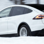 Tesla Model X kör genom snöigen terräng. (AI text)