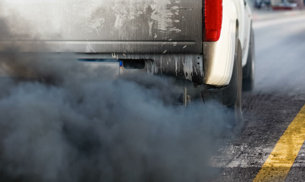 En lastbil med en svart utluftare kör ner gatan. (AI text)