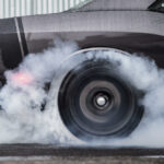 En svart Dodge Challenger sprutar rök. (AI text)