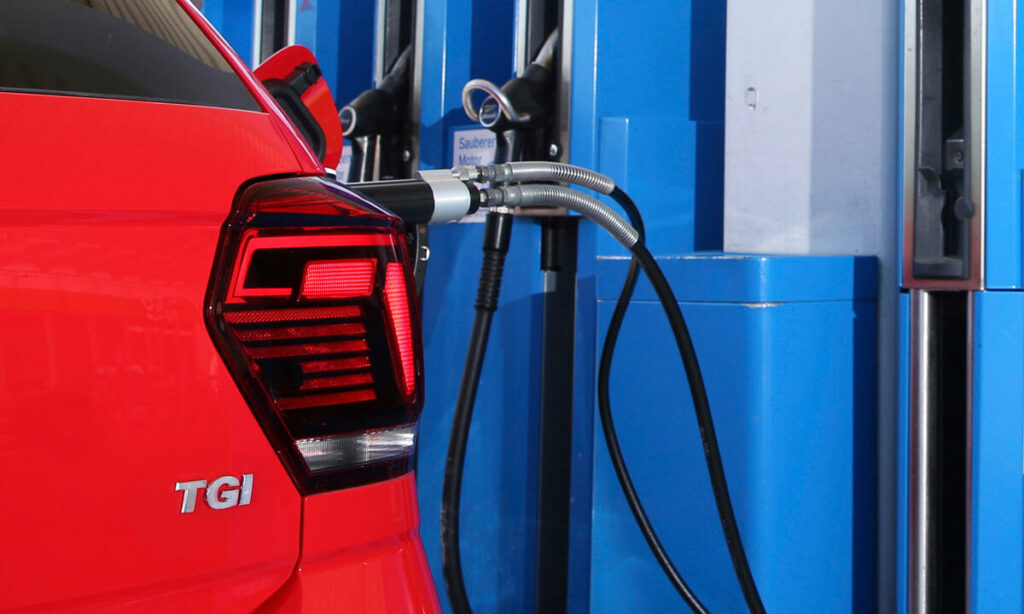 En röd Volkswagen TTS (170 TKMR) är parkerad vid en bensinstation. (AI text)