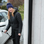 En kvinna laddar sin bil på en laddstation. (AI text)