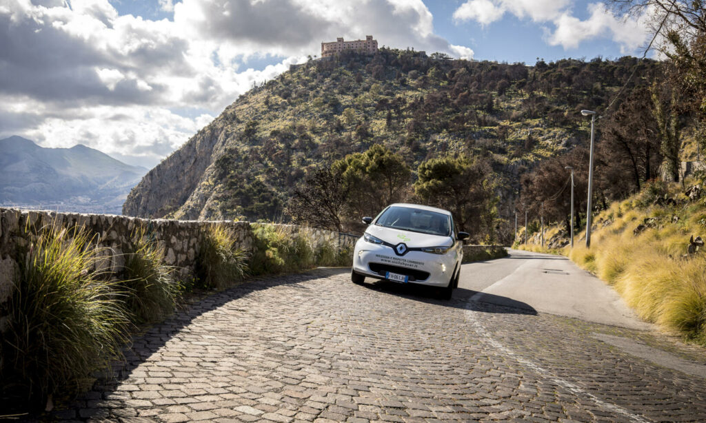 En bil kör nerför en stenlagd gata. (AI text)