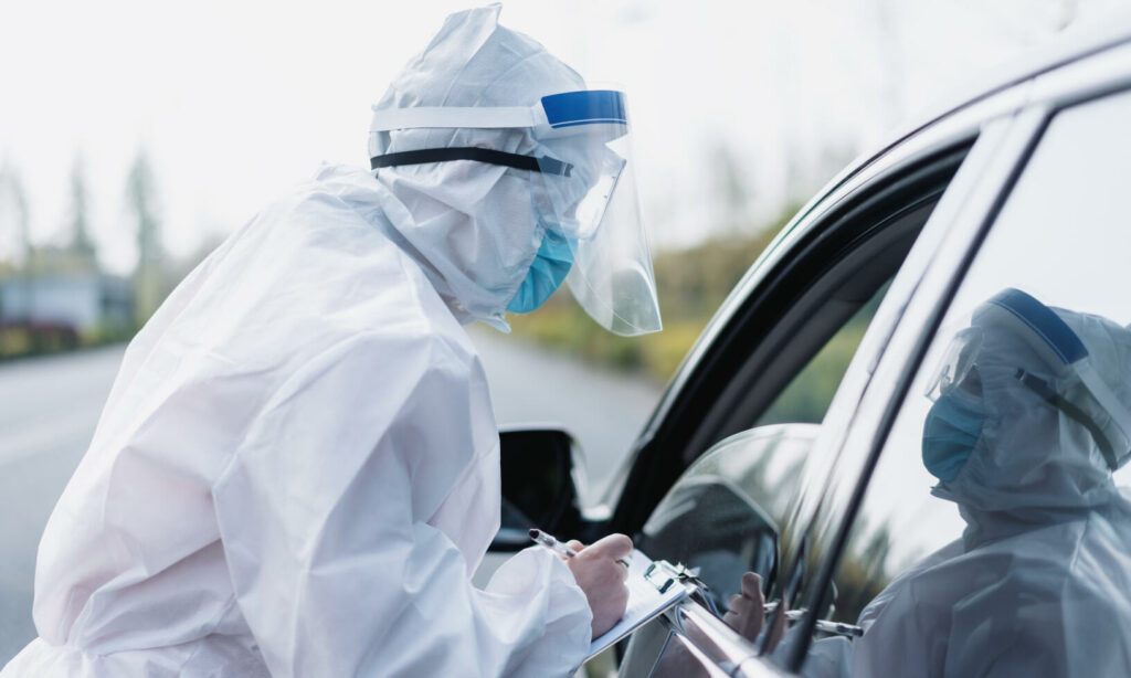 En man i skyddsutrustning öppnar dörren till en bil. (AI text)