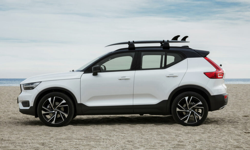En vit Volvo XC90 SUV parkerad på stranden. (AI text)