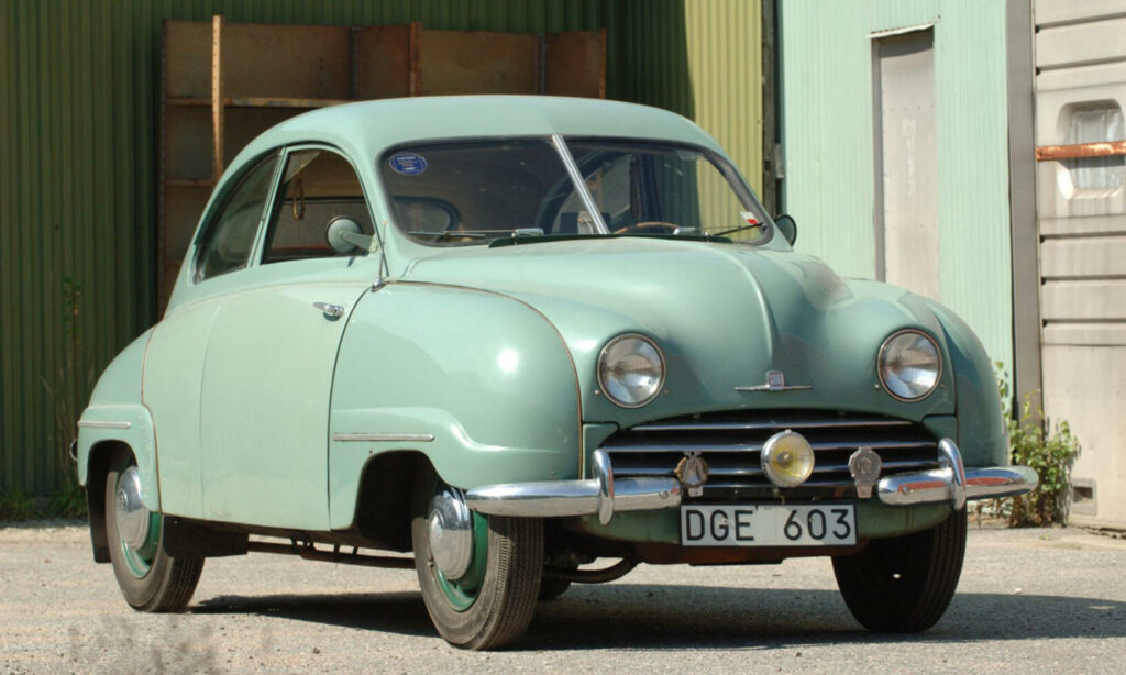 En grön bil parkerad framför ett byggnad. (AI text)