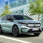 En grön Skoda IQ kör nedför en stadsgata. (AI text)