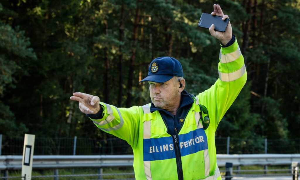 En polis officer dirigerar trafiken på en motorväg. (AI text)