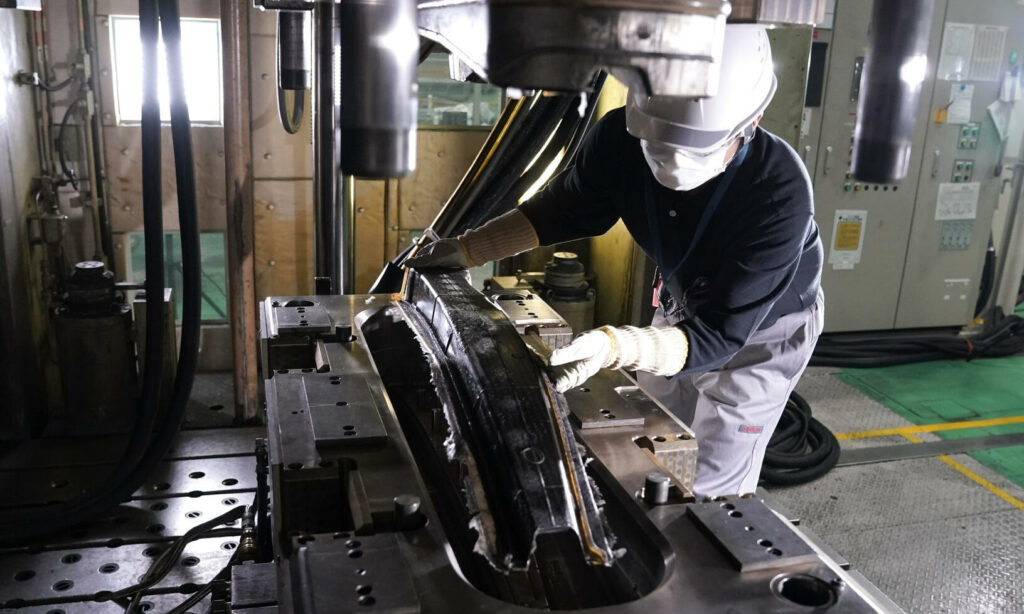 En arbetare arbetar på en bil i en fabrik. (AI text)