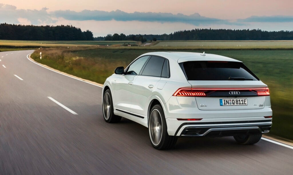 En Audi Q7 SUV kör nedför en landsväg. (AI text)