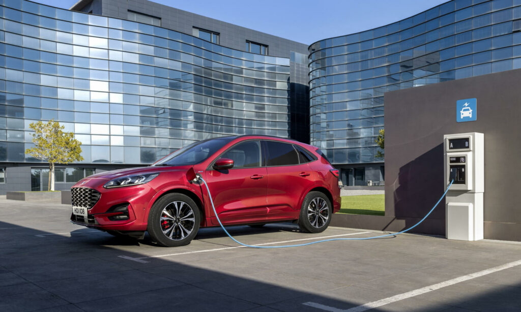 En röd Ford Kuga kopplad till en elladdare. (AI text)