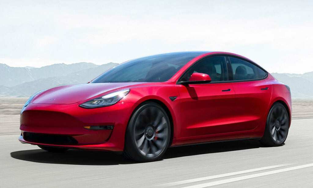 En Tesla Model 3 kör på en väg. (AI text)
