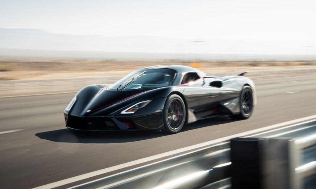 En svart sportbil kör nedför en väg. (AI text)