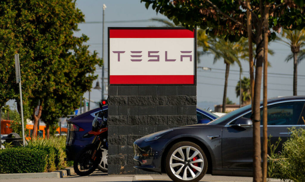 En Tesla Model S parkerad framför en Tesla-skylt. (AI text)