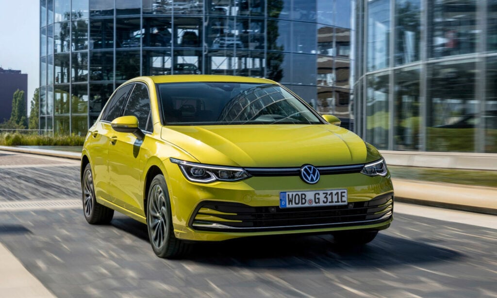 En gul Volkswagen Golf kör fram på en stadsgata. (AI text)