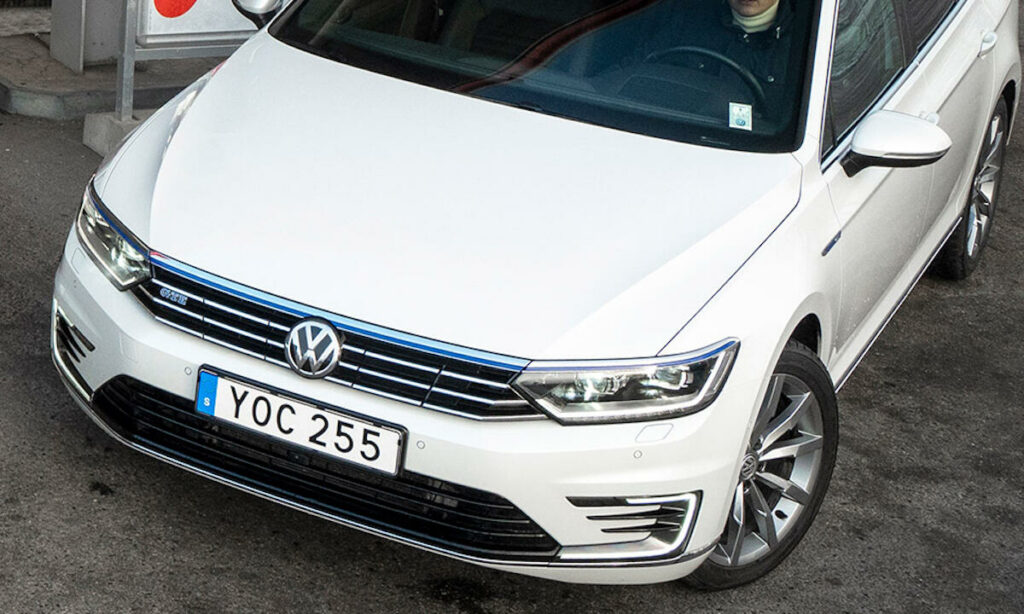 En vit Volkswagen Passat parkerad vid en bensinstation. (AI text)