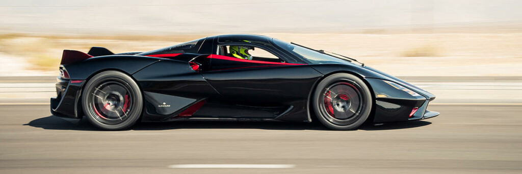 En svart sportbil kör nerför en ökenväg. (AI text)