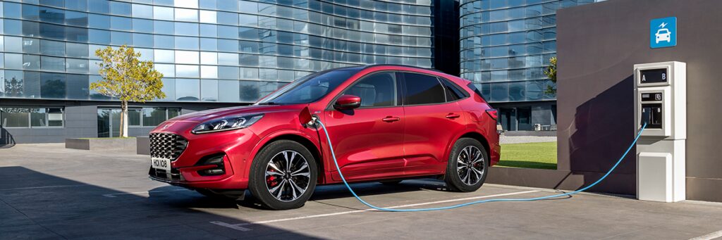 En röd Ford Evoque kopplad till en el-laddare. (AI text)
