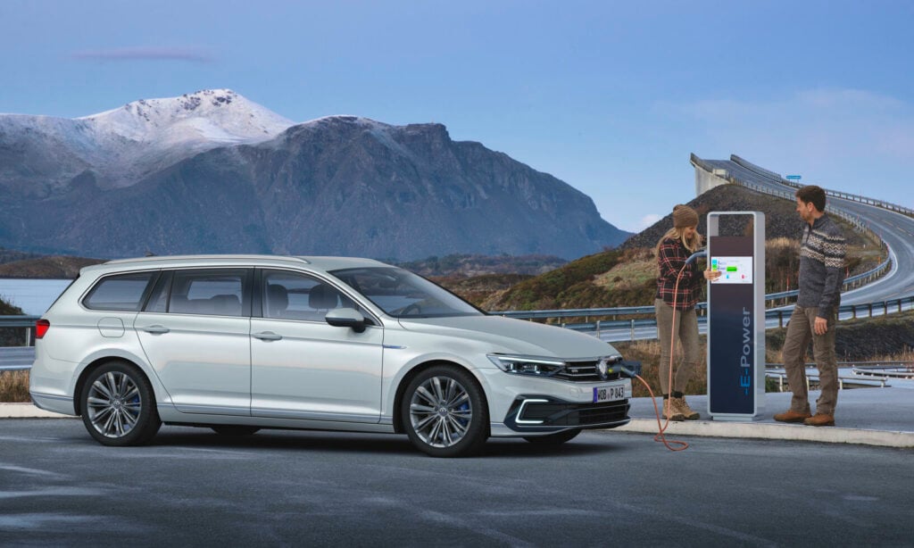 En vit Volkswagen Passat parkerad vid en elbilsladdstation. (AI text)
