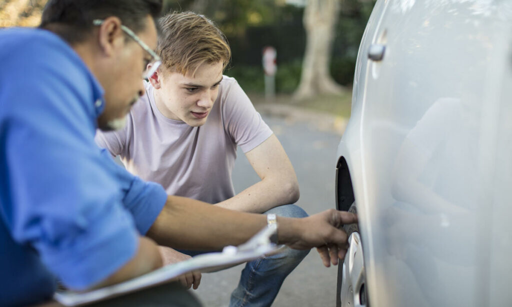 En man inspekterar hjulen på en bil. (AI text)