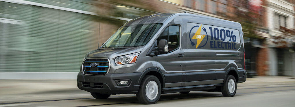 En Ford Transit-buss kör nedför en stadsgata. (AI text)