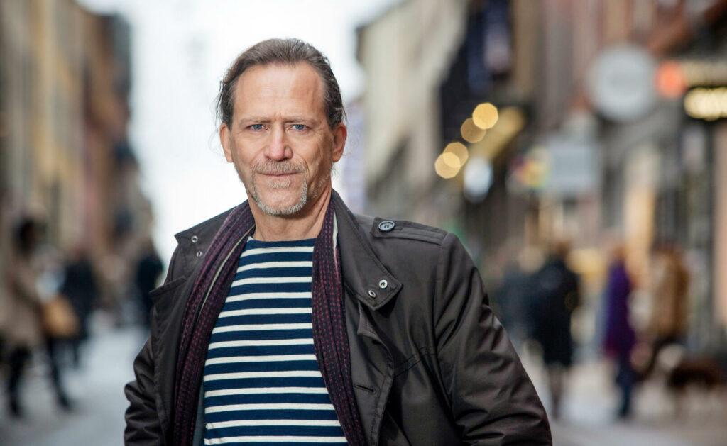 En man i läderjacka står på en stadsgata. (AI text)