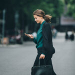 En kvinna går nedför gatan med sitt mobiltelefon. (AI text)