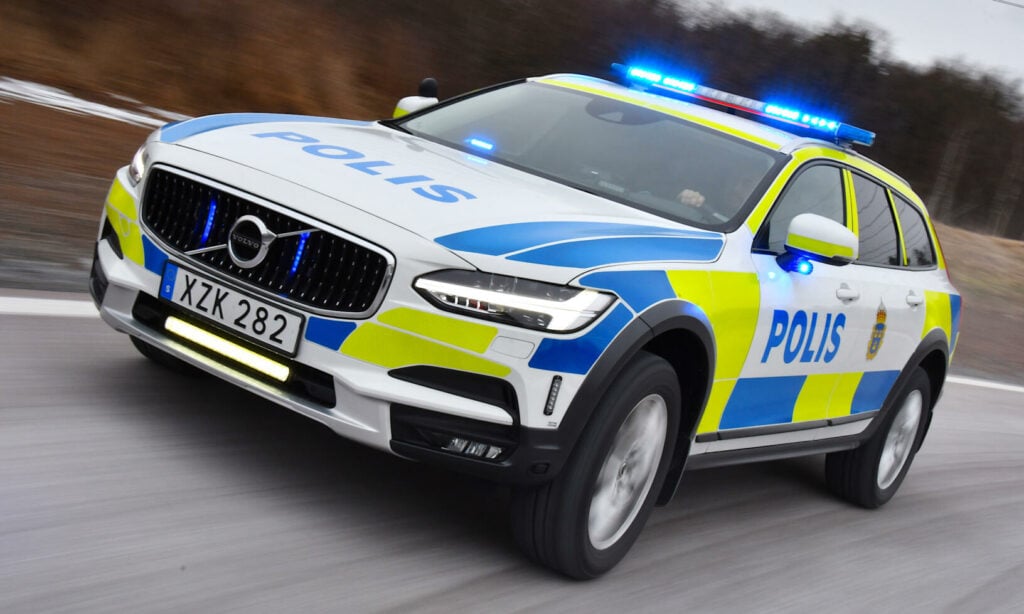 En polisbil kör ner en väg. (AI text)