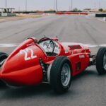 En röd racerbil kör längs banan. (AI text)