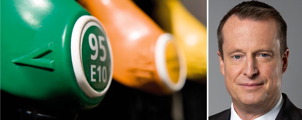 En man i kostym och slips står bredvid en bensinpump. (AI text)