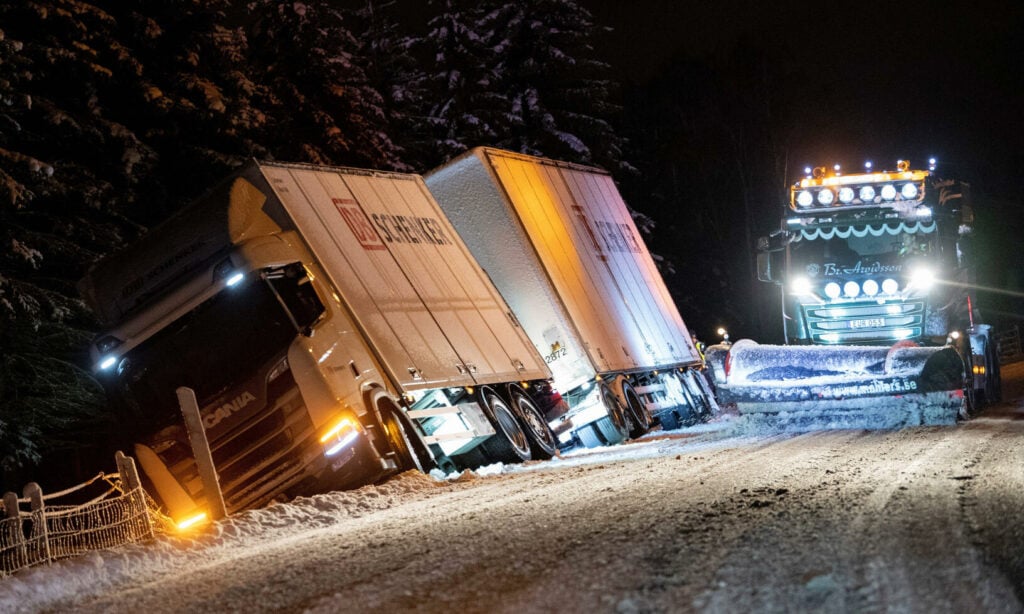 En lastbil står parkerad på en snöig väg. (AI text)